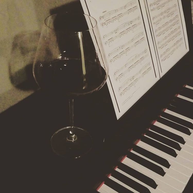 A wine glass, piano, and sheet music